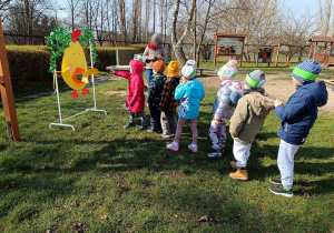 Dzieci rzucające papierową kulką w dziób papierowego kurczaka.