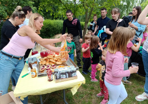 Rodziny czekające przy stoisku z bułkami mlecznymi z dżemem i kompotami.