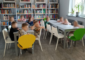 Dzieci słuchające książki czytanej przez panią bibliotekarkę.