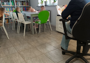 Dzieci słuchające książki czytanej przez panią bibliotekarkę.