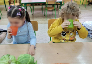 Dzieci piją sok marchewkowy.