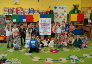 Dzieci prezentujące plakat stworzony z okazji Dnia Misia i swoje pluszaki.