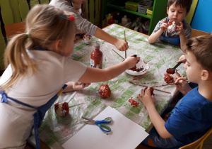 Dzieci malujące pączki z papieru.